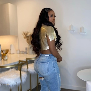 Dettaglio del crop top in maglia metallica dorata e jeans blu strappati in un bar