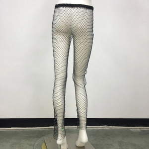 Dettaglio macro dei pantaloni neri in rete a vita alta con strass colorati scintillanti