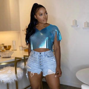 Dettaglio del top con paillettes blu lucide e pantaloncini di jeans denim