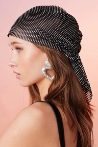 Detail of a black fishnet headpiece with sparkling rhinestones and a textured silver earring