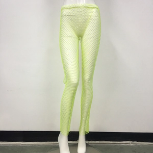 Dettaglio dei pantaloni a rete verde neon con strass scintillanti da festa