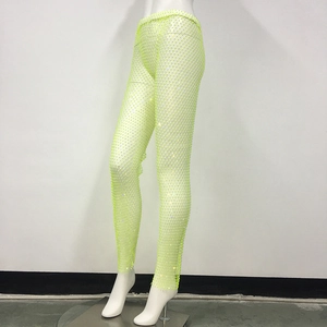 Dettaglio macro dei pantaloni a rete verde neon con strass brillanti su rete elastica