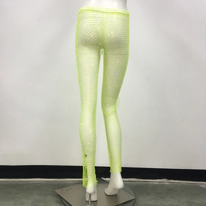 Dettaglio dei pantaloni a rete verde fluorescente con strass scintillanti su un manichino