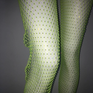 Dettaglio dei collant a rete verde fluo con strass scintillanti indossati dal modello
