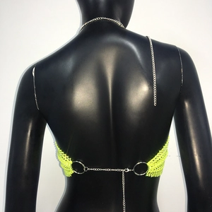 Dettaglio del top a rete giallo neon con catene metalliche e anelli sulla schiena