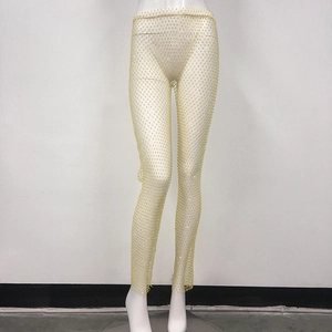 Dettaglio dei pantaloni a rete dorati con decorazioni in strass brillanti e trasparenti