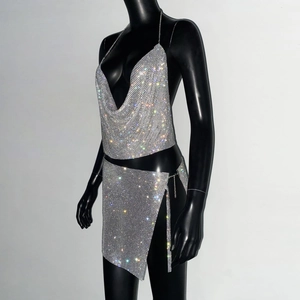 Dettaglio del crop top e minigonna in maglia metallica argento con catena strass