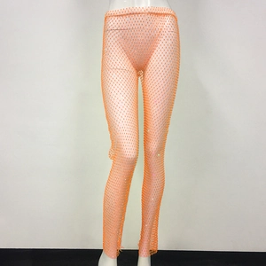 Dettaglio dei pantaloni in rete arancione con strass scintillanti e design traforato