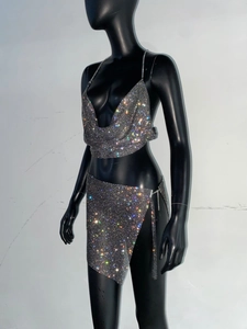 Dettaglio del set due pezzi in maglia di strass argento con top a fascia e minigonna spaccata