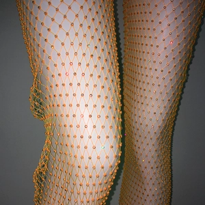 Dettaglio di pantaloni a rete arancione vivace con strass lucidi sulla struttura