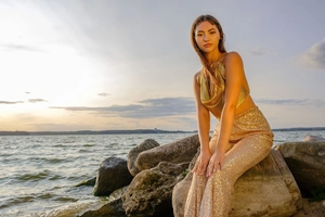 Détail du haut dos nu en maille dorée et du pantalon à paillettes sous le coucher du soleil