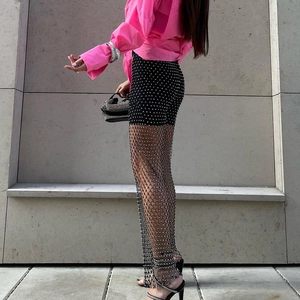 Pantaloni a rete neri sexy con strass, camicia rosa e borsa a mano argento trendy