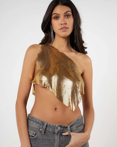 Détail du crop top en maille dorée avec épaule asymétrique et ourlet en biais élégant