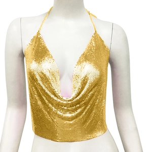 Détail du crop top à paillettes dorées avec col en V profond et fines chaînes dorées