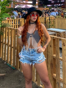 Women's festive rhinestone fringe halter crop top paired with distressed denim shorts