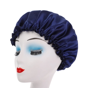 Dettaglio della cuffia da notte in raso blu scuro con bordo elastico a balze su manichino