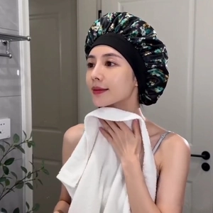Floral satin sleep bonnet with wide elastic band worn by model in bathroom setting