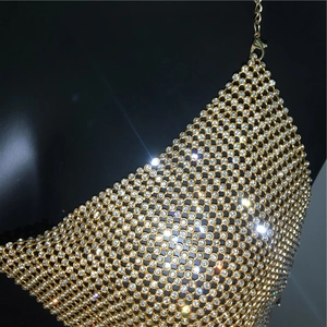Détail d'un haut en maille strass dorée scintillante avec chaîne et fermoir en métal