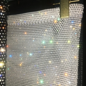 Close-up of sparkling white fishnet mesh fabric with reflective rhinestones for party skirts