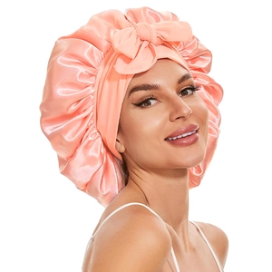 Pink satin sleep bonnet with a decorative bow for long hair protection and night care
