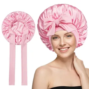 Detail of pink satin sleep cap featuring a smooth silk-like finish and a decorative bow tie