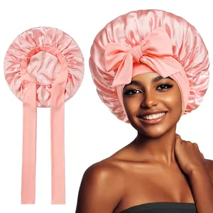 Detailed view of pink satin sleep bonnet with wide silk ribbons and decorative bow