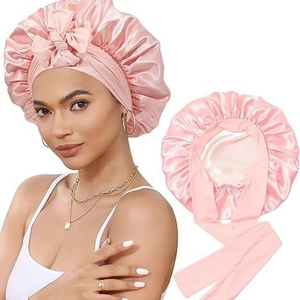 Detail of pink satin sleep bonnet with adjustable ribbon bow and smooth silk-like texture