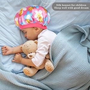 Close-up of pink silk bonnet for children with floral and ladybug prints on a sleeping toddler
