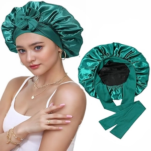 Dark green satin hair bonnet with wide ribbon bow and black lining for sleep care