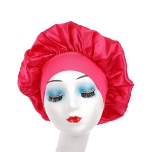 Detail view of the wide elastic band on a red satin sleep bonnet for hair protection
