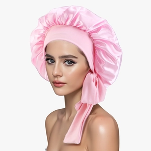 Pink satin sleep cap for hair care with wide elastic ribbon on a white background
