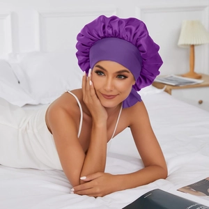 Deep purple satin sleep cap for women featuring a wide elastic band in a cozy bedroom setting