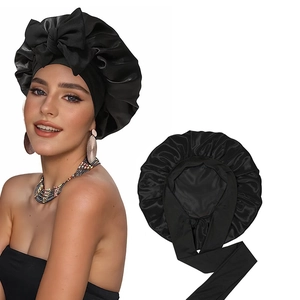 Detail view of black satin bonnet with adjustable elastic strap and bow for hair care