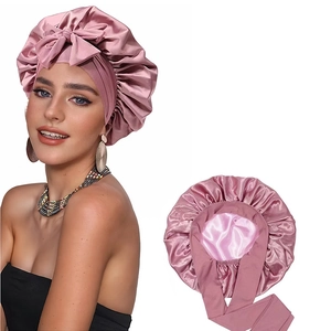 Detail of pink satin sleep bonnet with bow tie and wide band for hair protection