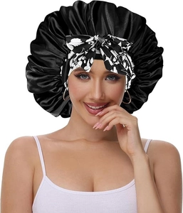 Detail of black satin sleep bonnet with a floral print bow tie for hair protection