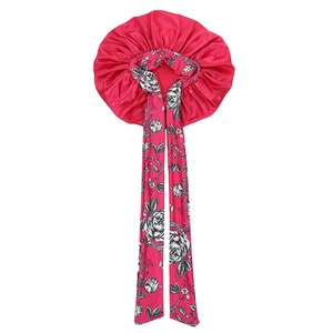Detail of rose pink satin hair bonnet featuring elegant black floral print on ties
