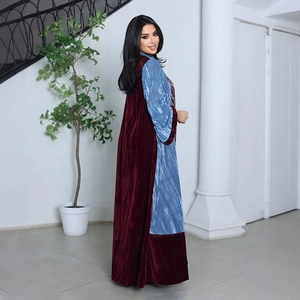 Detail of burgundy velvet and light blue pleated fabric on a long elegant abaya