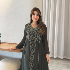 Détails de broderie complexe et de perles géométriques sur robe en mousseline vert foncé