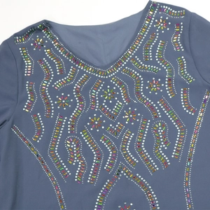 Détail d'une robe en mousseline à col en V avec des motifs de perles strass multicolores