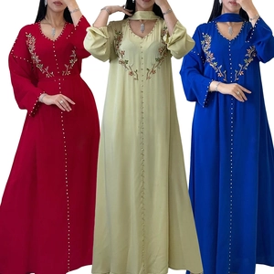 Dettaglio del ricamo floreale con paillettes su abiti kaftani rossi, verdi e blu