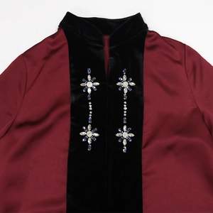 Detail of velvet patchwork on burgundy satin robe with blue gemstone floral embroidery