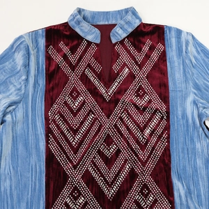 Detail of burgundy velvet robe with V-shaped rhinestone patterns and blue patchwork sleeves