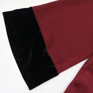 Detail of burgundy satin robe sleeve with contrasting black velvet cuffs and fine stitching