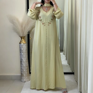 Dettaglio di ricamo floreale e maniche a lanterna su un abito Abaya verde chiaro con scollo a V