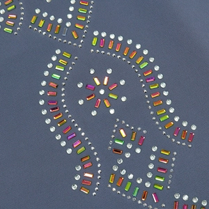 Détail macro de strass colorés formant des motifs floraux sur un tissu bleu marine