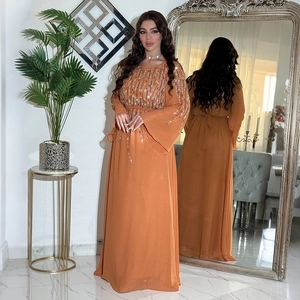 Dettaglio dell'abito lungo in chiffon arancione con paillettes e maniche lunghe ampie