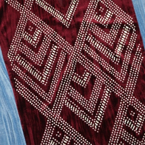 Macro shot of burgundy velvet fabric with detailed rhinestone and sequin geometric pattern