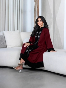 Elegant wine red velvet patchwork abaya with floral embroidery on a minimalist sofa