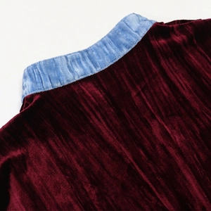 Detail view of burgundy velvet robe featuring contrasting blue collar and rhinestone accents