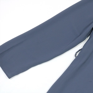 Détail d'une robe en mousseline gris-bleu avec coutures fines et passant de ceinture